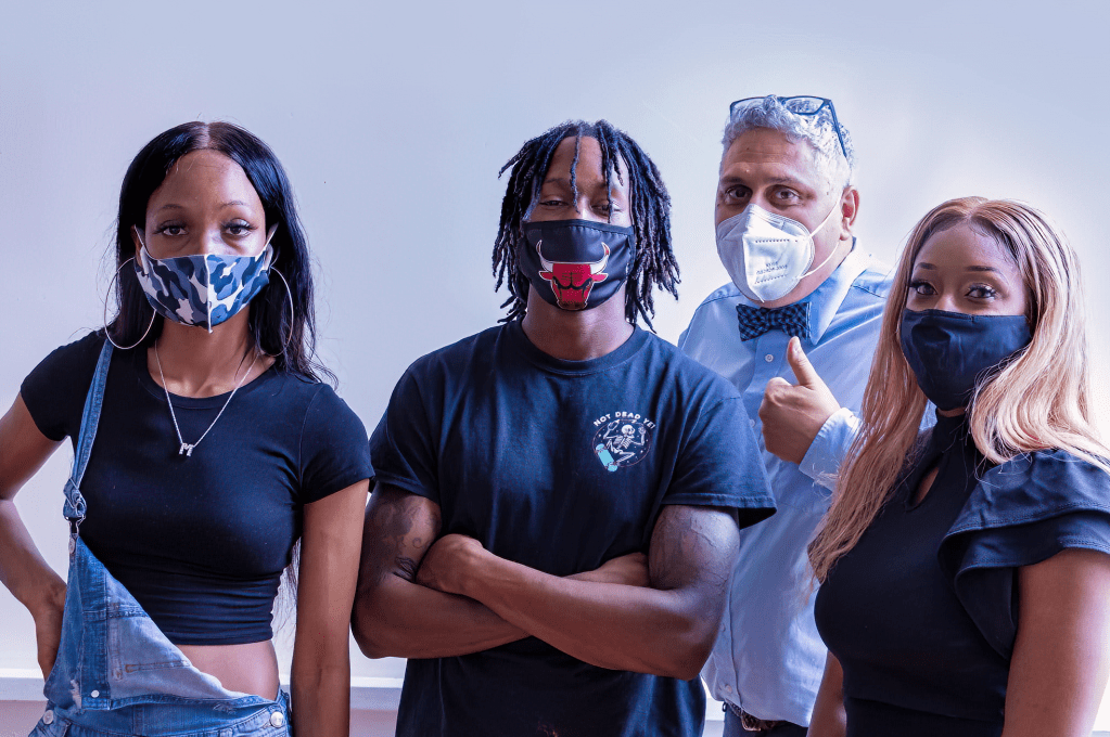 Luis Camillo standing with students in a portrait wearing masks.
