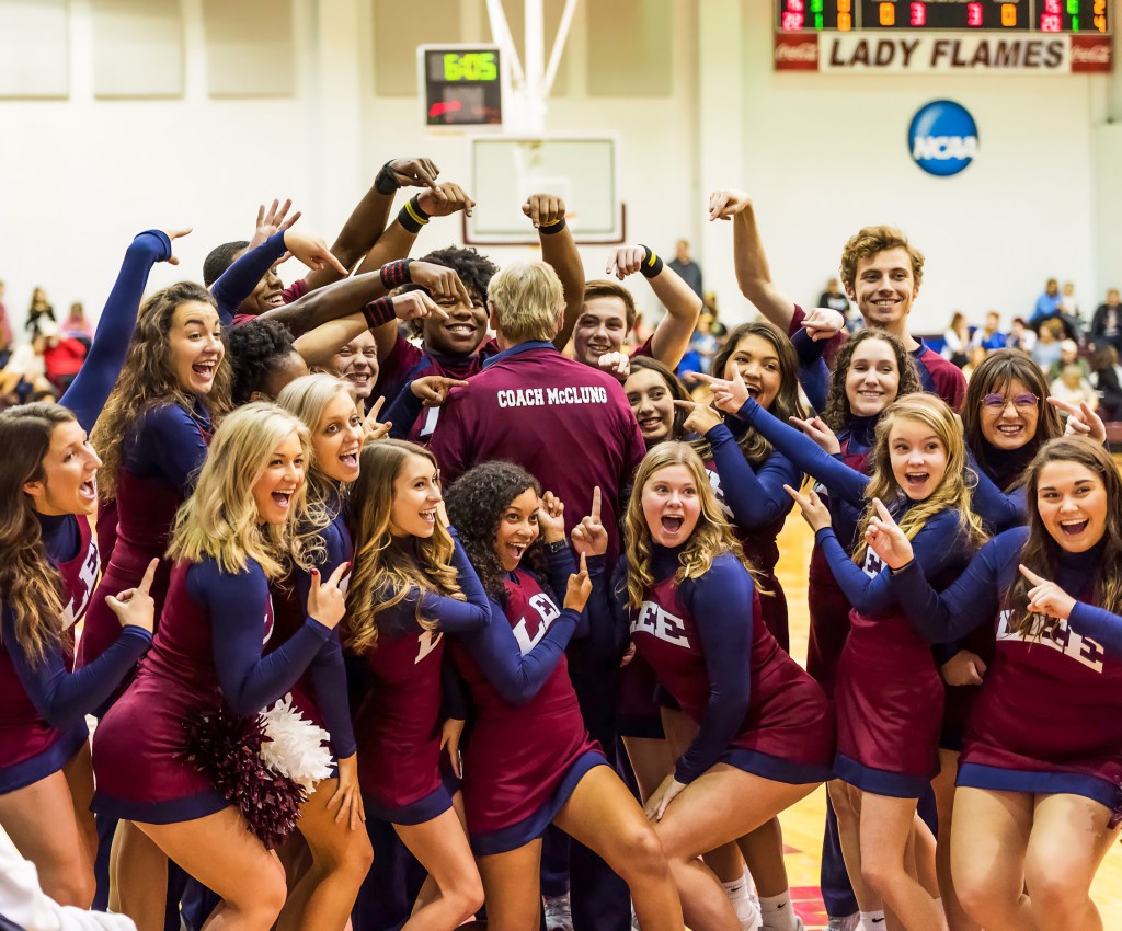 Dean of Students being celebrated by cheerleaders, smiling as they perform in recognition.